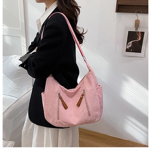 Pink corduroy crossbody bag detail showing symmetric zippers and brown leather pulls