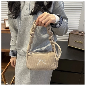 Detail of light brown corduroy handbag with white embroidered bow and ruched handle