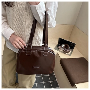 Close-up of the glossy chocolate brown faux leather texture and silver ring strap detail