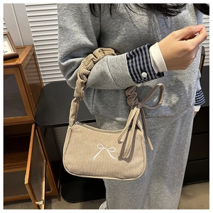 Detail of corduroy shoulder bag featuring bow embroidery and ruffled scrunchie strap