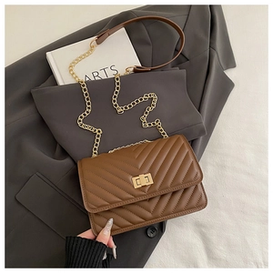 Detailed view of brown V-quilted faux leather crossbody bag with gold rectangular clasp