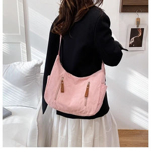 Side view of pink corduroy crossbody bag with double vertical zippers on female model