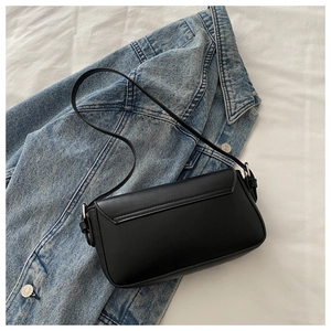 Close-up of minimalist black matte faux leather shoulder bag on a denim jacket