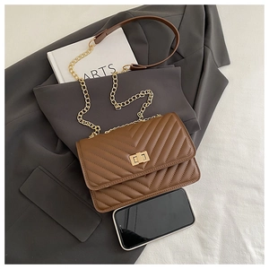 Detail of brown V-quilted leather shoulder bag with gold chain strap and square twist lock