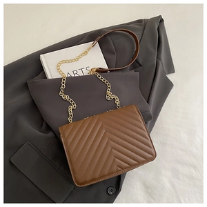 Detail of brown V-quilted faux leather crossbody bag with gold metal chain strap