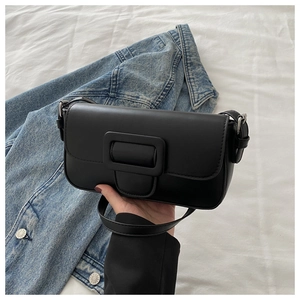 Detail of a black faux leather flap bag with a large square buckle and adjustable strap