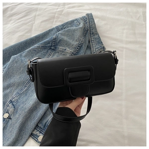 Detail of black PU baguette bag featuring a large decorative buckle on a denim background