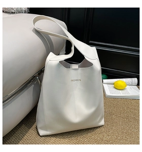 Detail of white tote bag with golden FASHION text on a grey sofa and woven rug