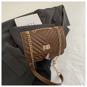 Close-up of brown quilted crossbody bag with gold square twist lock and chain strap