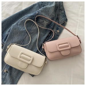 Close-up of minimalist square flap bags in cream and pink on blue denim jacket