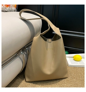 Macro detail of a beige leather tote bag with FASHION embossed logo and wide strap