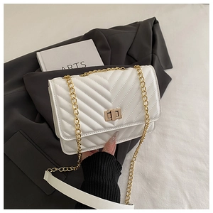 Close-up of white chevron quilted bag with golden twist lock and metal chain strap