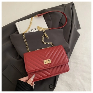Detail of red V-quilted small square bag with golden twist lock and chain strap