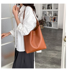 Brown leather tote bag featuring a gold FASHION slogan shown in an urban setting