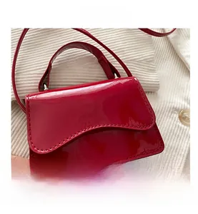 Close-up of red glossy patent leather mini handbag showing its texture and strap detail