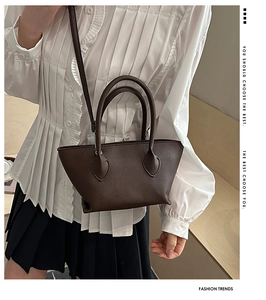 Detail of dark brown lychee grain leather bucket bag with top handles and shoulder strap