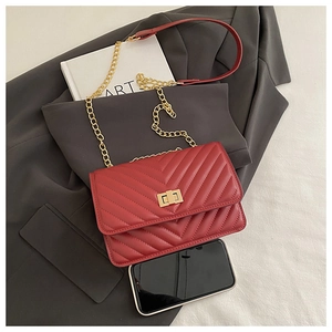 Macro shot of red quilted crossbody bag with gold chain strap and turn-lock closure