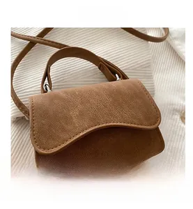 Detail of camel brown grain leather mini handbag with wavy flap and silver hardware