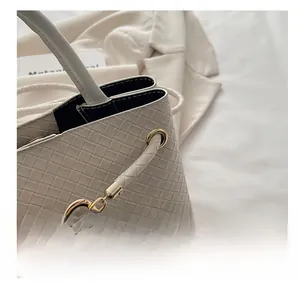 Close-up of beige woven leather texture and elegant gold metallic buckle on handbag