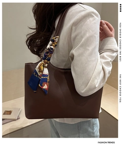 Detail of dark brown leather tote bag with decorative geometric silk scarf on handle