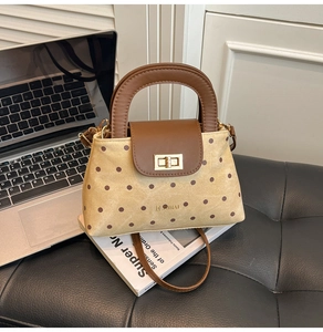 Détail du sac rétro à pois avec poignée en cuir et fermoir rotatif doré métallique