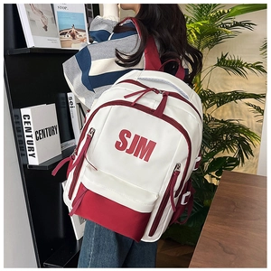 Detail of red and white school backpack with SJM logo and durable side straps