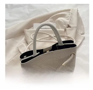 Detail view of cream woven handbag showing golden chain, neat stitching, and multi-compartment interior