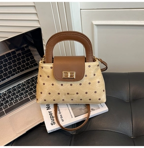 Détail d'un sac à main rétro à pois avec rabat en cuir et fermoir doré sur un bureau