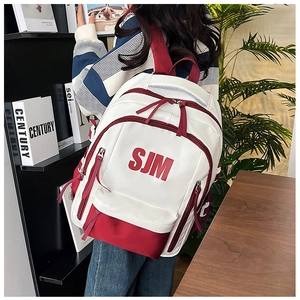 Student backpack with red SJM logo on white waterproof nylon worn in a study setting