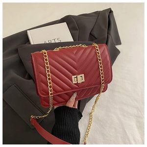 Detail of red chevron quilted crossbody bag with gold twist lock and chain strap