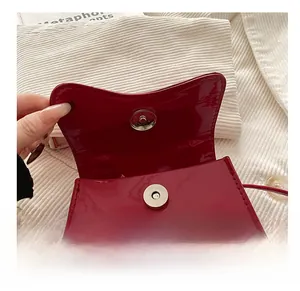 Detailed macro view of high-quality metal magnetic closure on a red patent leather bag