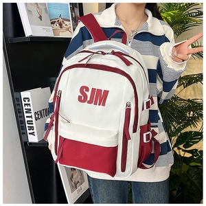Detail of red and white contrast backpack featuring SJM letter print and side buckles