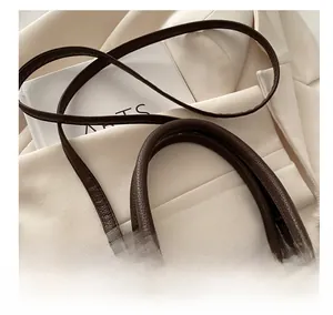 Macro detail of brown pebble leather bucket bag with silver buckle and shoulder strap