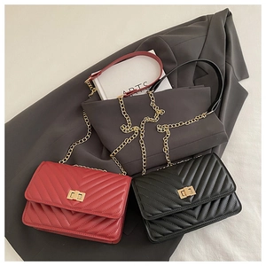 Detail of red and black quilted chain bags with gold clasps on a grey suit background