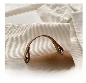 Detail of brown faux leather handbag showing lychee texture and silver metal rings