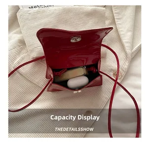 Macro view of red patent leather mini bag showing interior storage for lipstick and earbuds