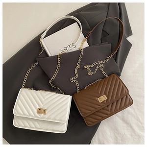 Detail of white and brown quilted crossbody bags with V-shaped stitching and gold chain