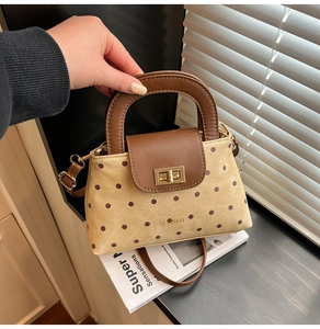 Détail du sac à main en toile à pois avec rabat en cuir et fermoir rotatif doré