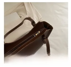Detail of brown leather tote bag with white stitching and decorative scarf accessory