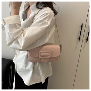 Close-up of a pink faux leather shoulder bag with a large buckle worn by a model