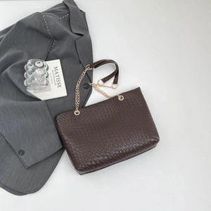 Dark brown crocodile pattern tote bag with gold chain strap on grey blazer background