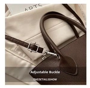 Close-up of adjustable metal buckle on dark brown lychee grain leather handbag strap
