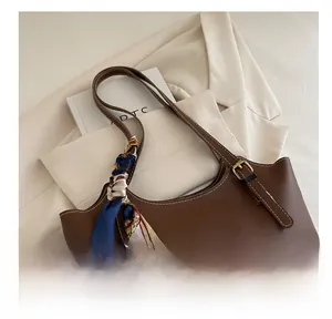 Detail of dark brown tote bag with contrast stitching and decorative silk scarf on handle