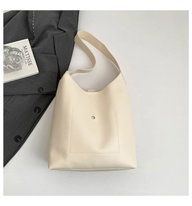 Close-up of cream faux leather tote bag with metal buckle and wide shoulder strap detail