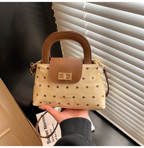 Détail du sac bandoulière en toile à pois avec bordure en cuir et fermoir doré tournant