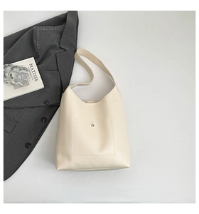 Close-up of cream faux leather tote bag showing front pocket with magnetic clasp
