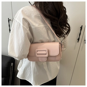 Model wearing a light pink flap shoulder bag with a matte finish and square buckle detail