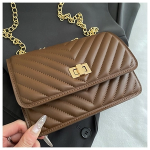 Detail of a brown quilted crossbody bag with golden clasp and elegant chain strap