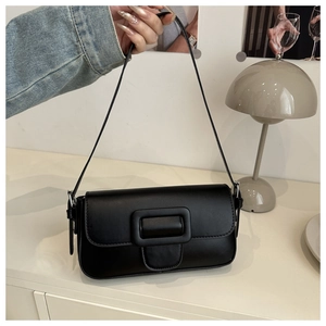 Detail of a minimalist black baguette shoulder bag with a large square leather buckle