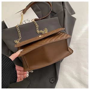 Detail of a brown quilted crossbody bag showing base width and golden chain strap